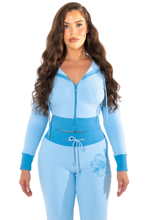 Woman wearing a light blue tracksuit with a floral design on a white background